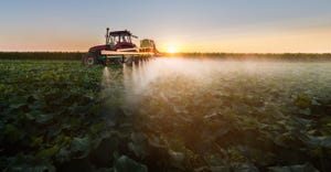tractor spraying pesticide on soybean plants