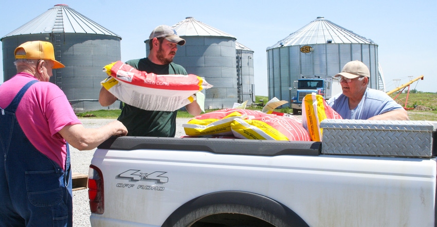 Farmers packing seed bags into the bed of a truck Farmers packing seed bags into the bed of a truck