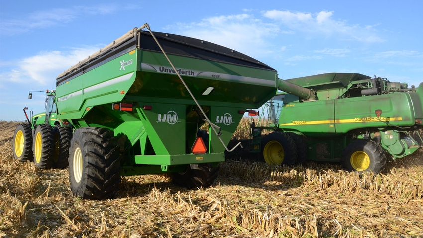 John Deere combine, grain cart and tractor sitting in harvested cornfield