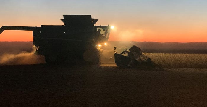 combine harvesting at sunset