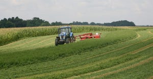 A tractor out in a field harvesting alfalfa