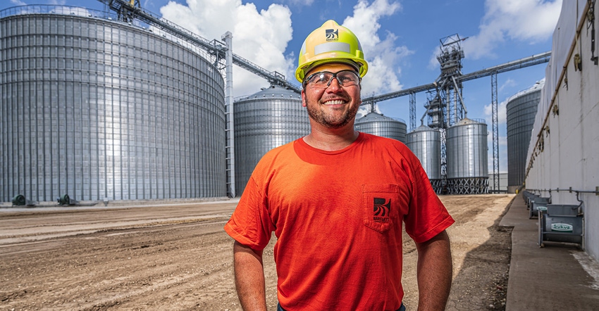 Facility worker in front of grain bins and facility