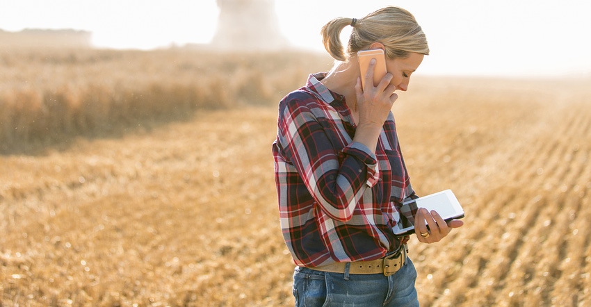female farmer with smartphone and tablet in field