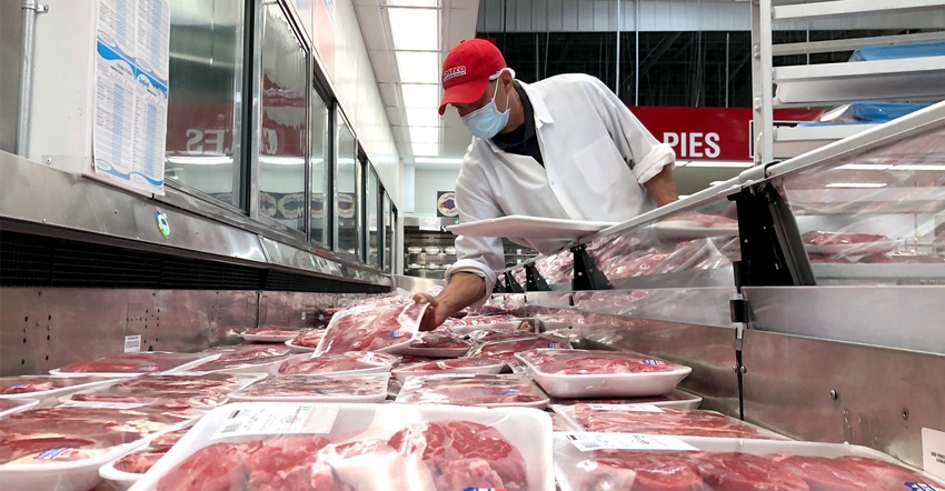 Butcher stocking a display case with steaks