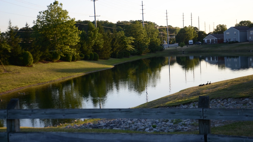 retention pond on outskirts of subdivision surrounded by power poles and trees