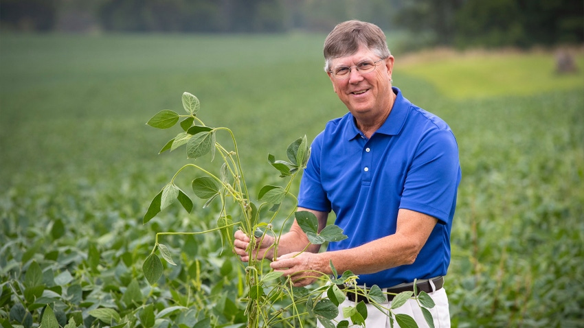 Ron Kindred poses near a soybean plant