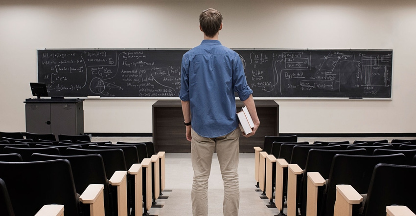 Student standing in classroom looking at chalkboard