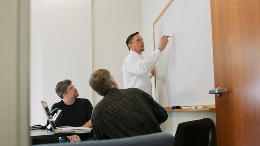 teacher writing on board while students look on