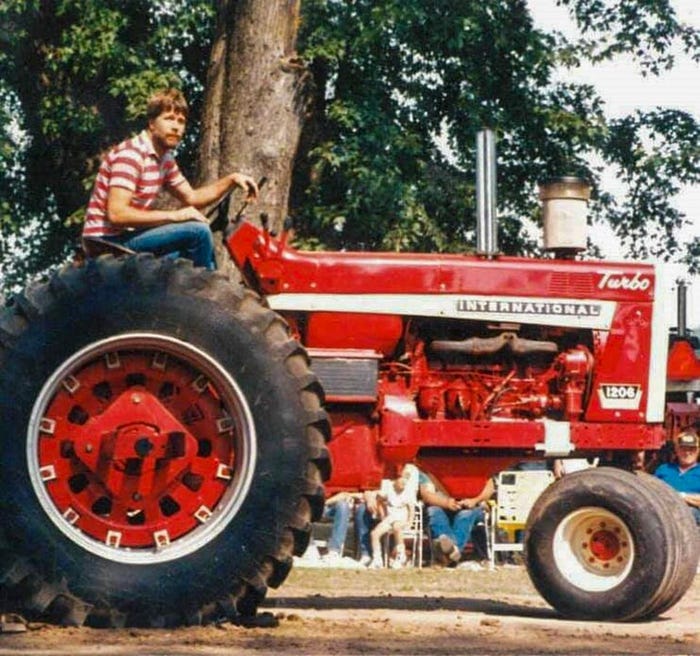 An old photograph of Doug Allen sitting on a red tractor
