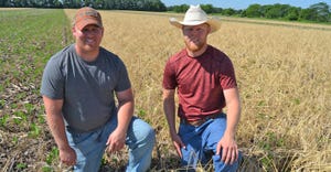 Brothers Travis (left) and Cody Brinker kneel in soybean field that was planted into standing cover crop