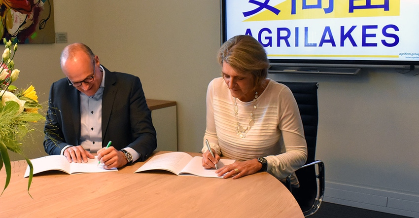Two people signing an agreement at a table. It says Agrilakes in the background