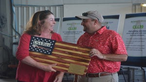 A woman and a man holding a wooden representation of the American flag