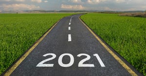 2021 written on paved road leading off into horizon through farm fields.