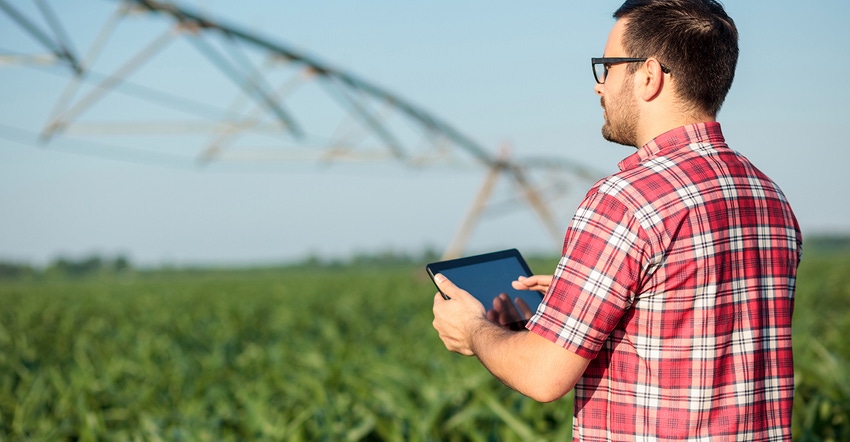 young farmer with tablet in irrigated field