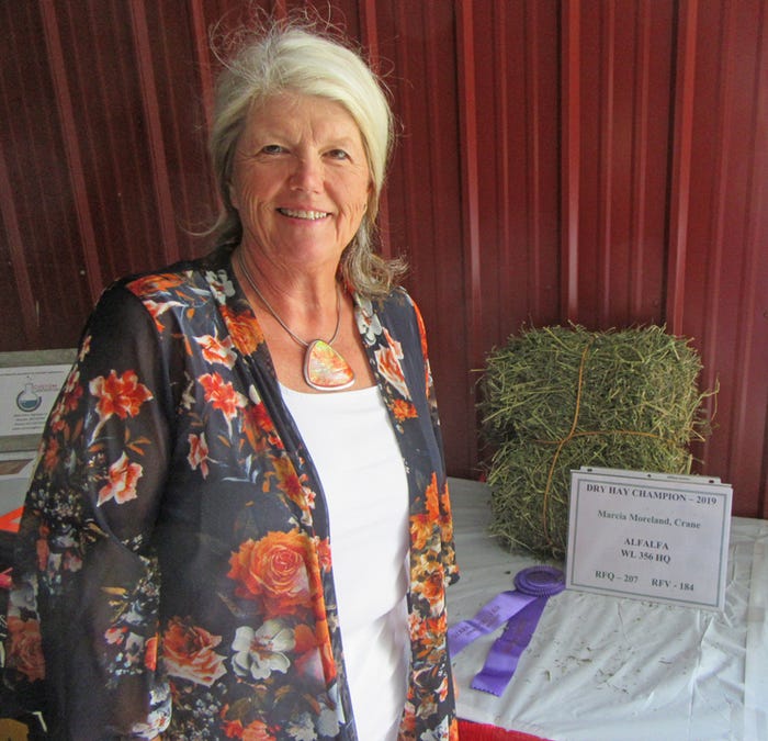 Marcia Moreland stands next to hay sample and first place certificate earned in dry hay class at the 2019 Ozark Empire Fair Hay Show