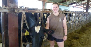 Lucy Kniebuehler in dairy barn with a Holstein cow