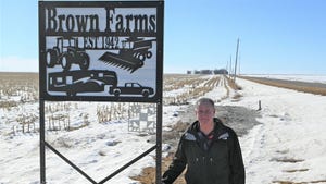 Jim Brown standing next to Brown Farm sign