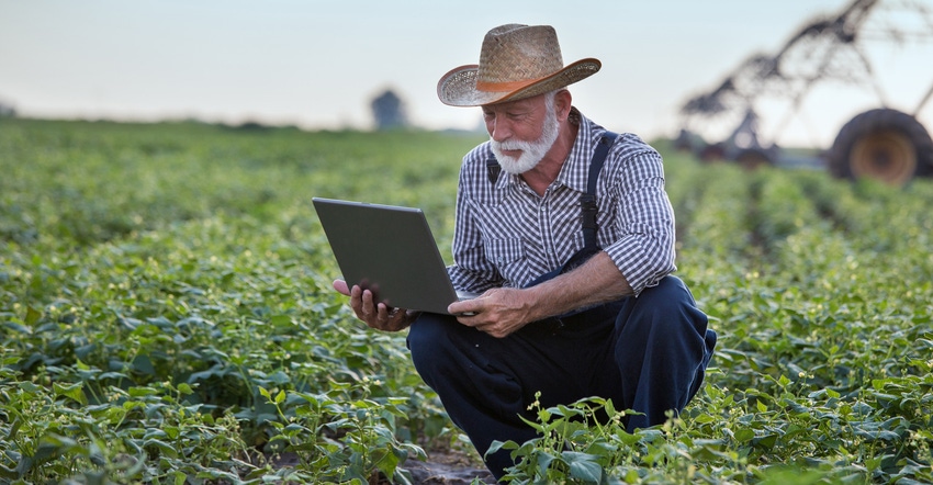 Farmer with a laptop in the middle of a field