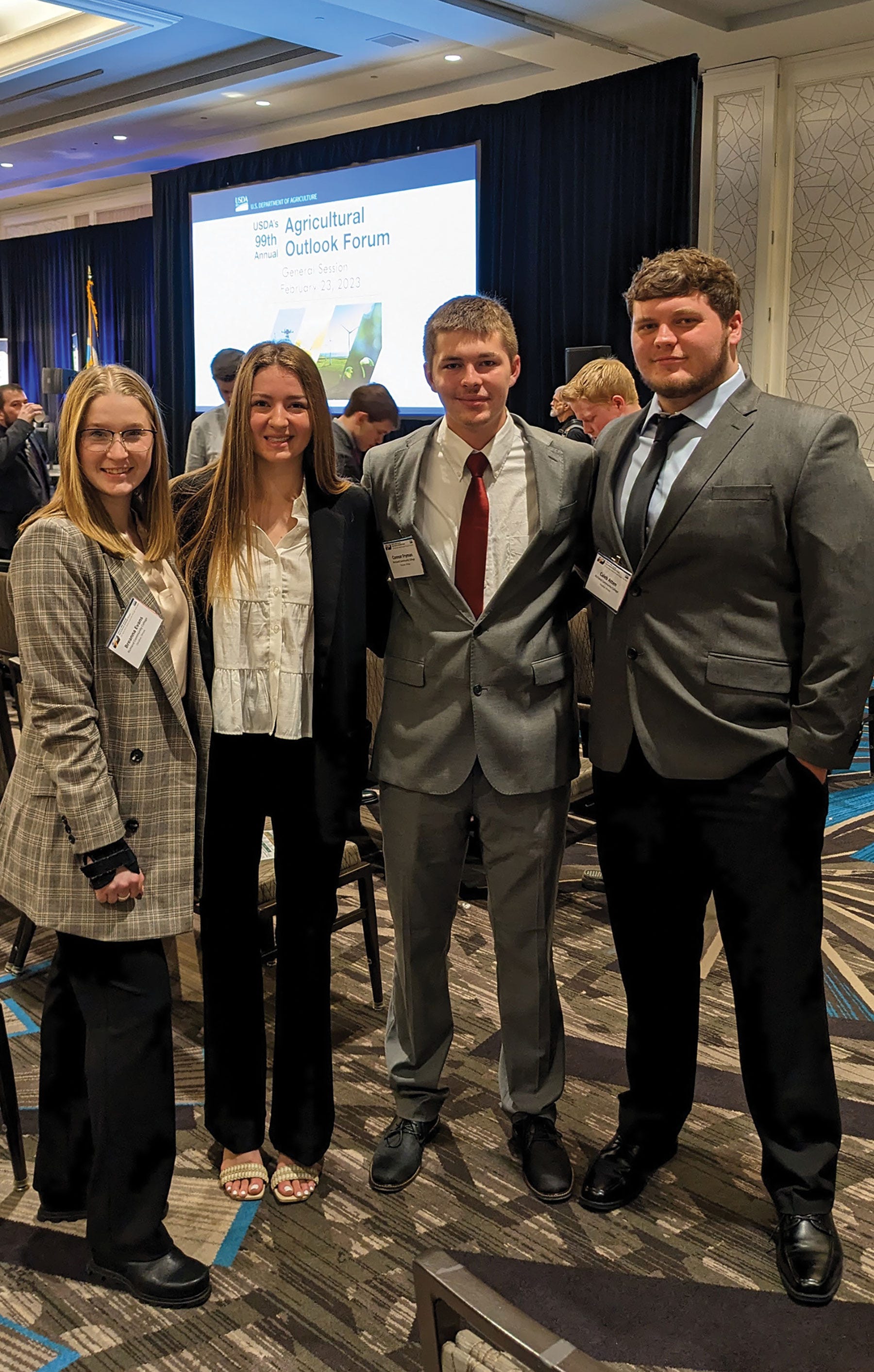 two young women and two young men in formal business attire at a conference