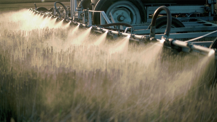 Close up details of tractor nozzles spraying herbicides on a field