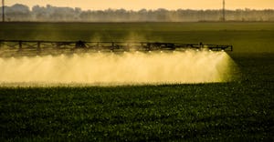 Jets of liquid fertilizer spray from the tractor sprayer