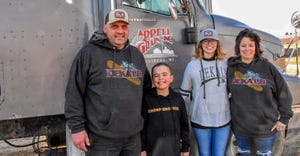 Tim, Wendy, Remington and Jada Appell posing in front of a tractor trailer