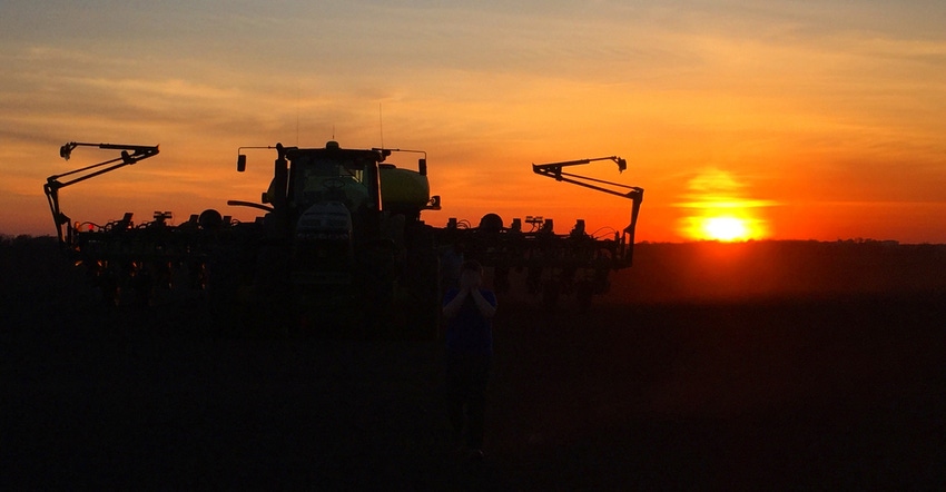 silhouette of tractor and planter at sunset