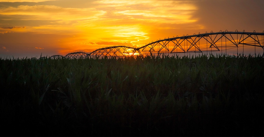 silhouette of irrigation equipment against sunset