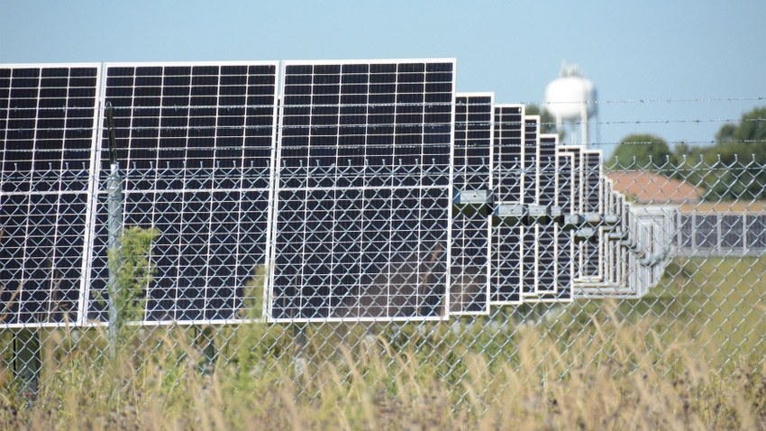 Solar panels behind a wired fence in a field