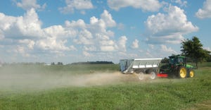 farm equipment spreads gypsum in a crop field