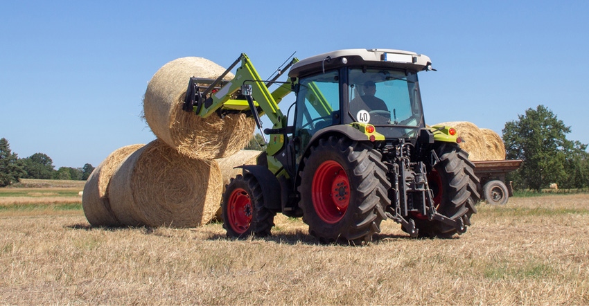 tractor in field loading hay