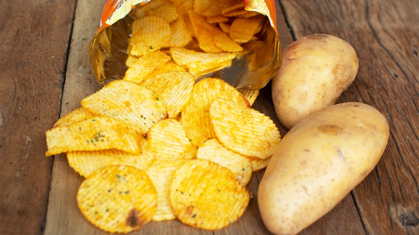 A bag of potato chips poured next to potato heads