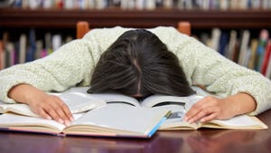 Shot of a female college student studying in a library and looking stressed