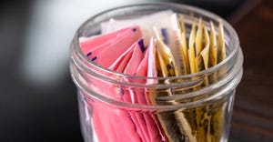 Assorted packets of artificial sweetener in a glass jar