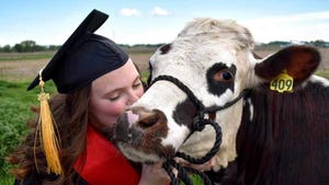 HALEI HEINZEL in a cap and gown, kissing a cow