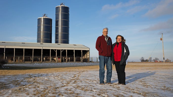 Ron and Deb Moore in front of their cattle barn and silos