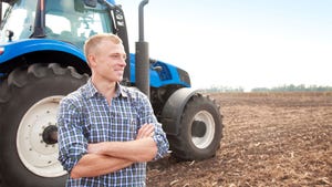 A young farmer near a tractor on a field