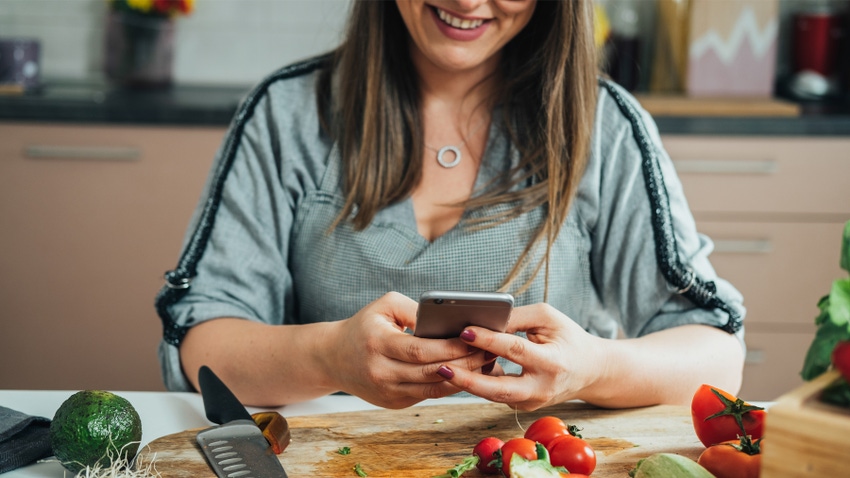 woman making salad and texting woman making salad and texting