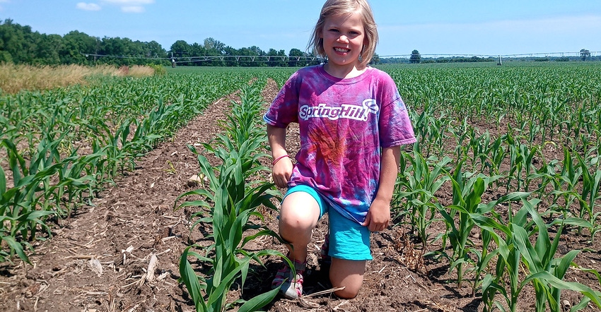 Girl kneeling in corn field