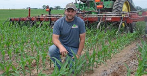 Brooks Cardinal kneeling in young corn field