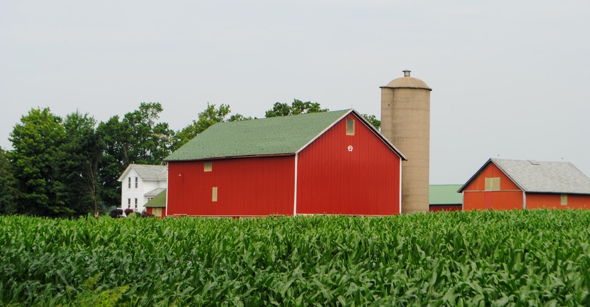 A red barn and farm house pictured in a field