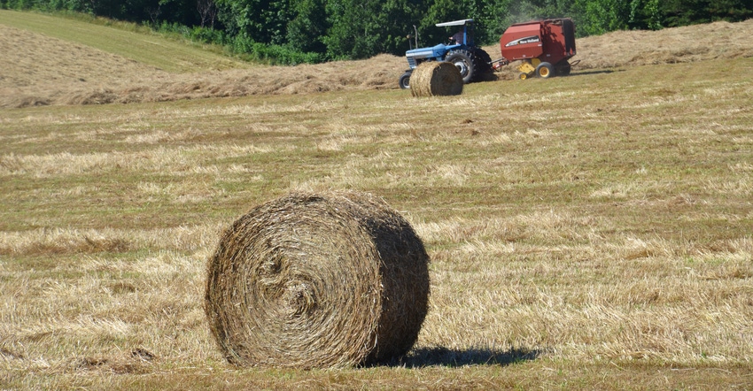 hay bale in field with tractor in background
