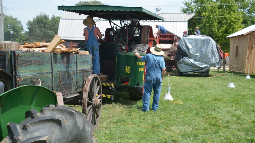 A steam engine prepared for a threshing demonstration connected to a trailer with a pile of wood