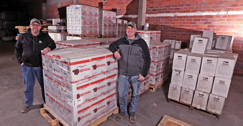 Two men standing in warehouse with boxes of inputs