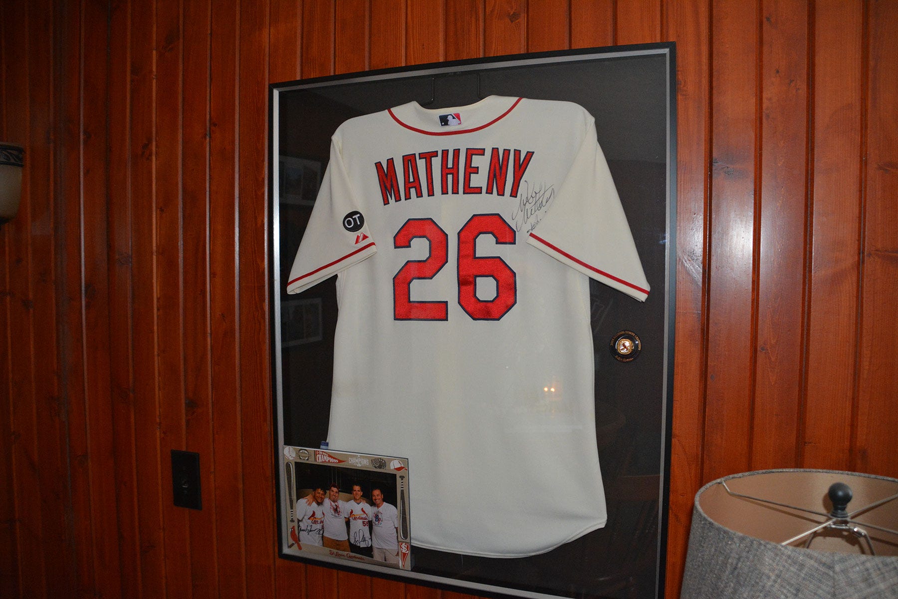 A framed Mike Matheny jersey hung on a wood-paneled wall