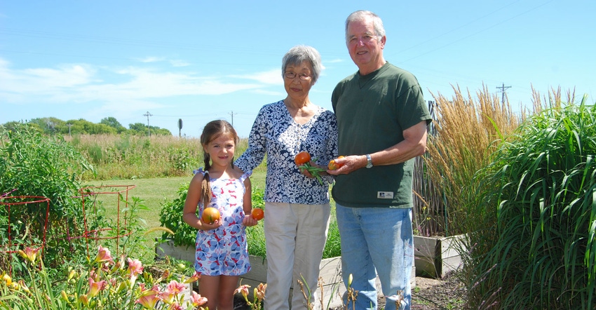 Yoshiko Johnson stands with her husband, Erwin Johnson, with their granddaughter Vivienne in the garden