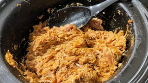 chicken taco meat in slow cooker with black spoon