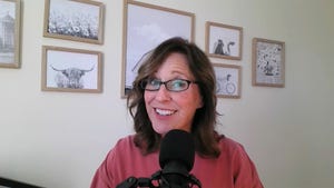 A screenshot of Mindy Ward smiling with a microphone in front