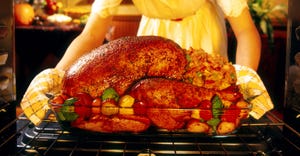 woman pulling turkey out of oven