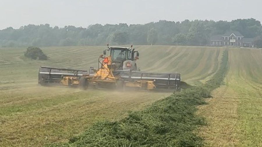 tractor and implement merging alfalfa in a field